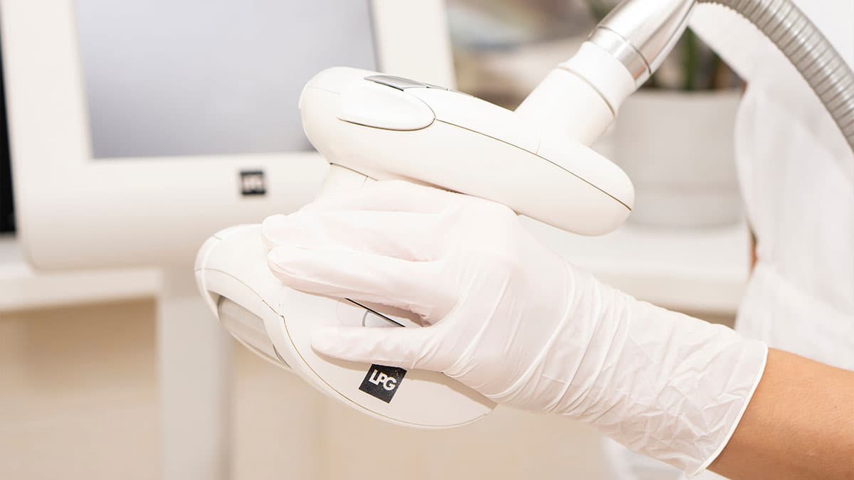 Close-up of an LPG Endermologie treatment head held by a gloved technician