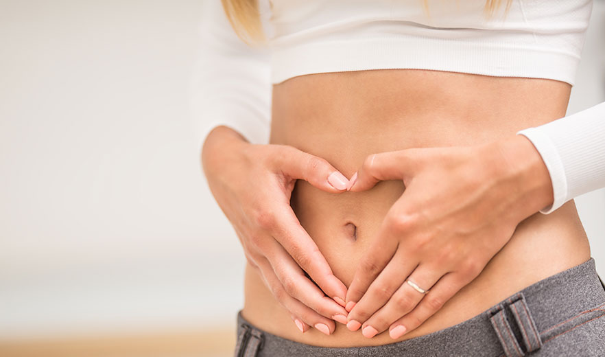 Belly of a health-conscious woman with hands arranged in the shape of a heart