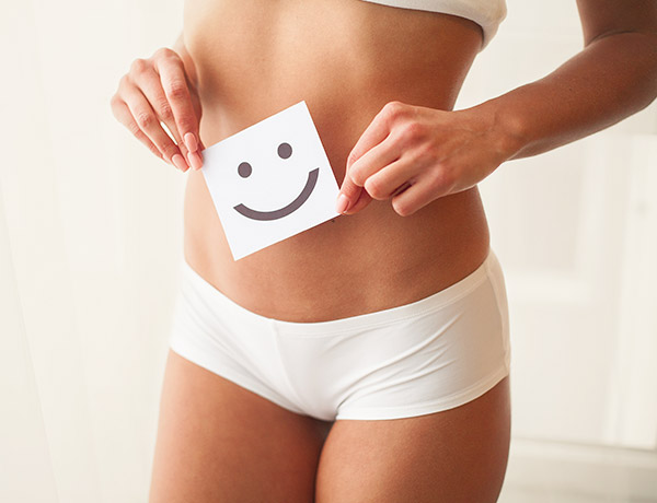 How to Prepare for Colon Hydrotherapy A person in white underwear holds a paper with a smiley face over their abdomen, symbolizing health and wellness.