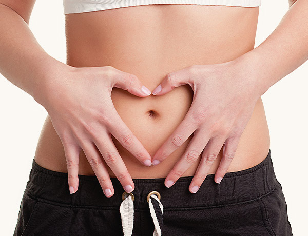 Colon Hydrotherapy Close-up of a person forming a heart shape with their hands over their stomach, symbolizing the benefits of colon hydrotherapy treatment.
