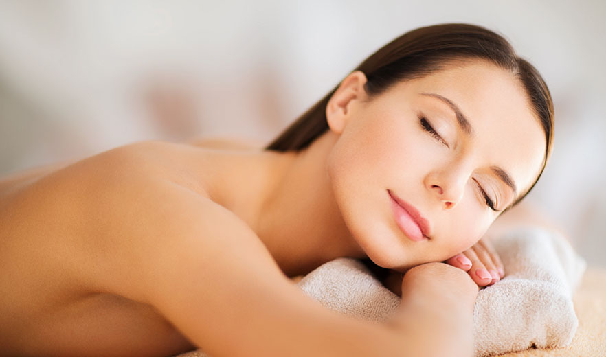 Woman relaxing on a massage table with a serene expression, symbolizing Endermologie for Wellness and Beauty.