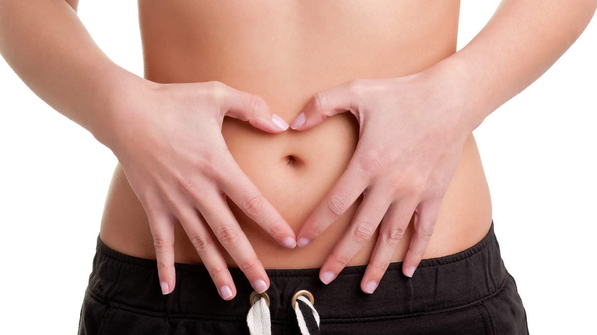 Hands forming a heart shape on a belly, symbolizing health and wellness.