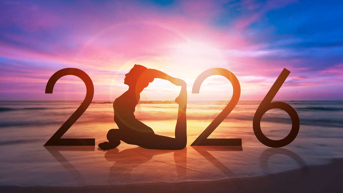 Silhouette of a person in a yoga pose at sunset on a beach, forming the number 2026 against a colorful sky.