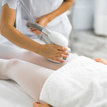 Endermologie body treatment on the thigh using a mechanical roller device, often used to support lymphatic flow and post-sedentary swelling.