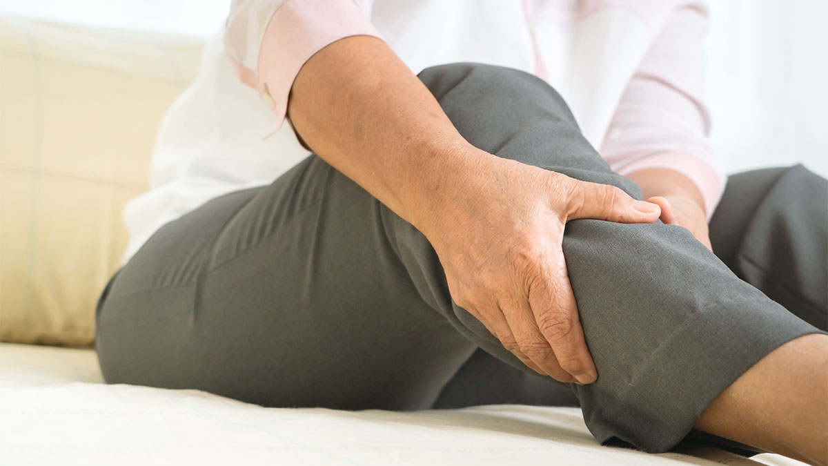 Person holding a swollen lower leg and ankle, illustrating leg heaviness and water retention after long periods of sitting or travel.
