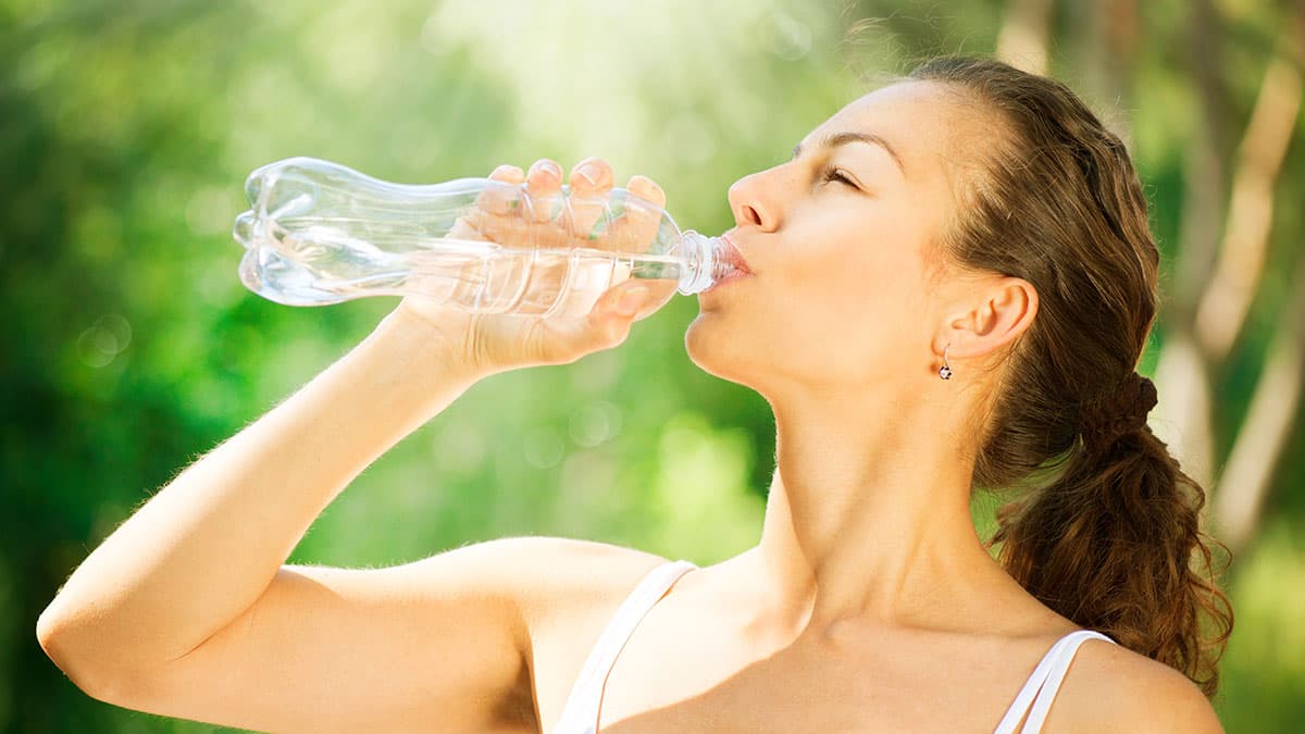 Woman drinking water outdoors after ionic foot bath session for hydration and aftercare
