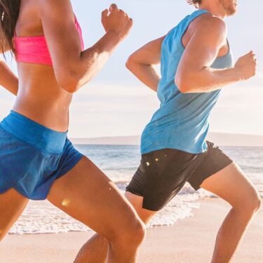 Two people running on a beach as part of a healthy wellness routine supported by colon hydrotherapy