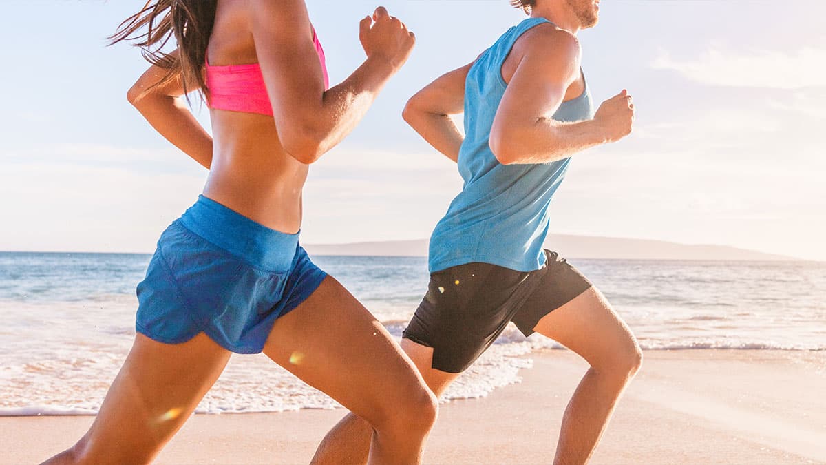 Two people running on a beach as part of a healthy wellness routine supported by colon hydrotherapy