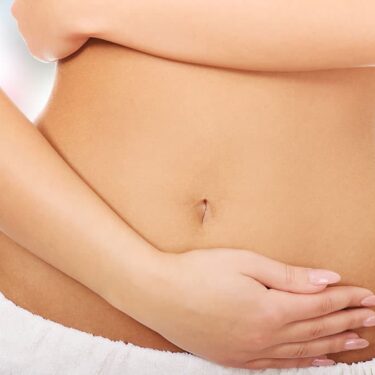 Woman holding her lower abdomen, representing digestive wellness and colon hydrotherapy in Bellevue, WA